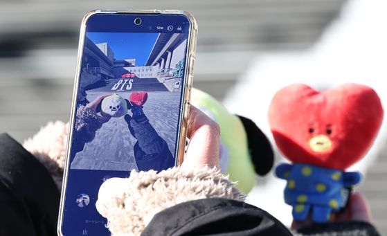 A person takes photos of BT21 Line character dolls in front of a promotional display for BTS’s fifth full-length album on the steps of the Sejong Center for the Performing Arts in central Seoul on Jan. 22. [NEWS1]
