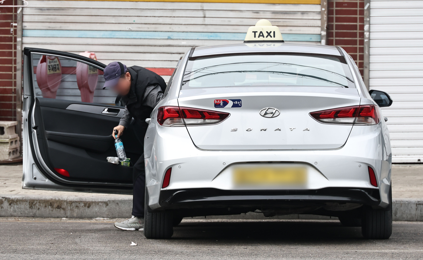 A taxi driver exits their vehicle in Seoul on Jan. 26. [YONHAP] 