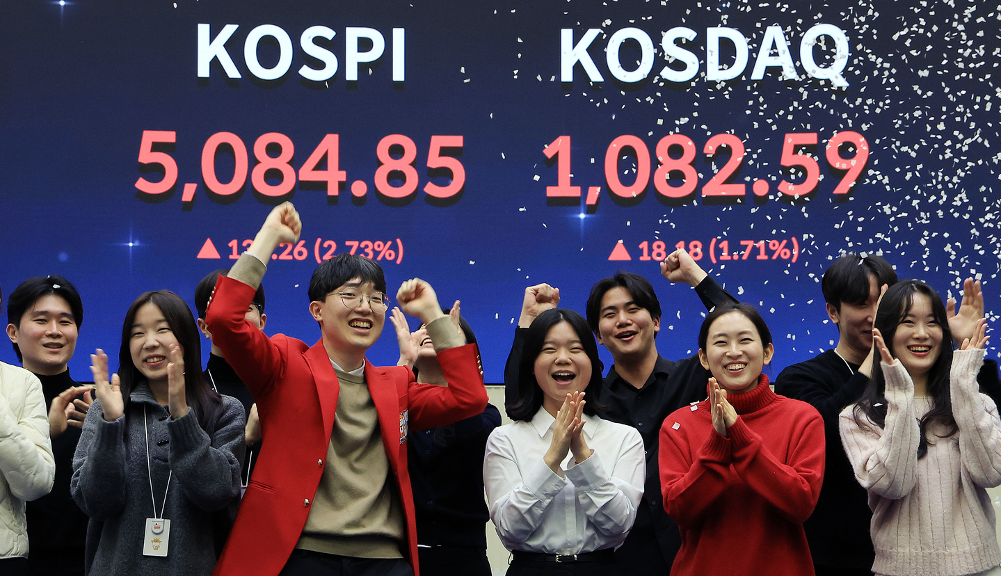 Employees celebrate in front of an electronic board showing the Kospi closing above 5,000 for the first time on Jan. 27 at the Korea Exchange in Yeongdeungpo District, western Seoul. [NEWS1]