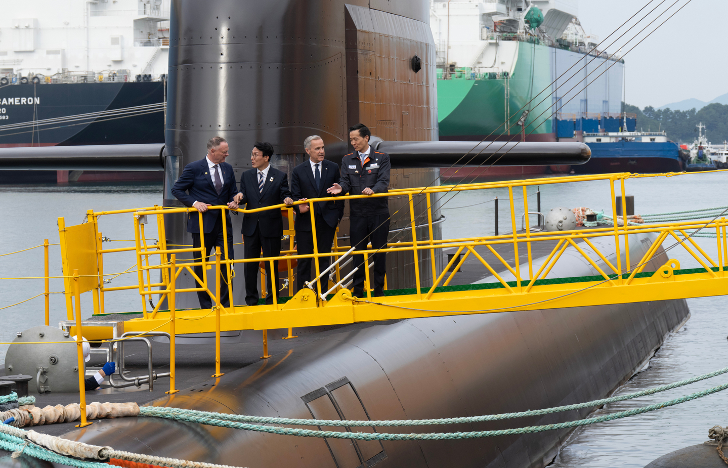 From left, Canadian National Defense Minister David McGuinty, Prime Minister Kim Min-seok, Canadian Prime Minister Mark Carney and Hahnwa Group Vice-Chairman Kim Dong Kwan talk amongst themselves after touring a submarine at the Hanwha Ocean Shipyard in Geoje Island, Korea, Oct. 30, 2025. [AP/YONHAP]