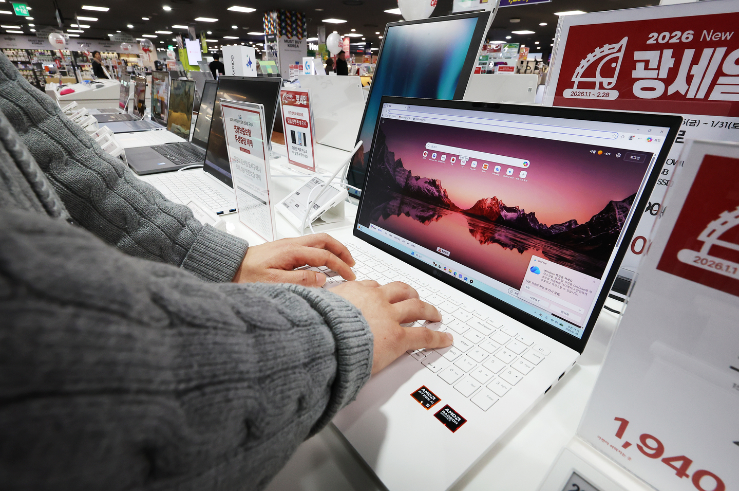 A store worker examines a laptop displayed at an electronics store in Seoul on Jan. 25. [YONHAP] 