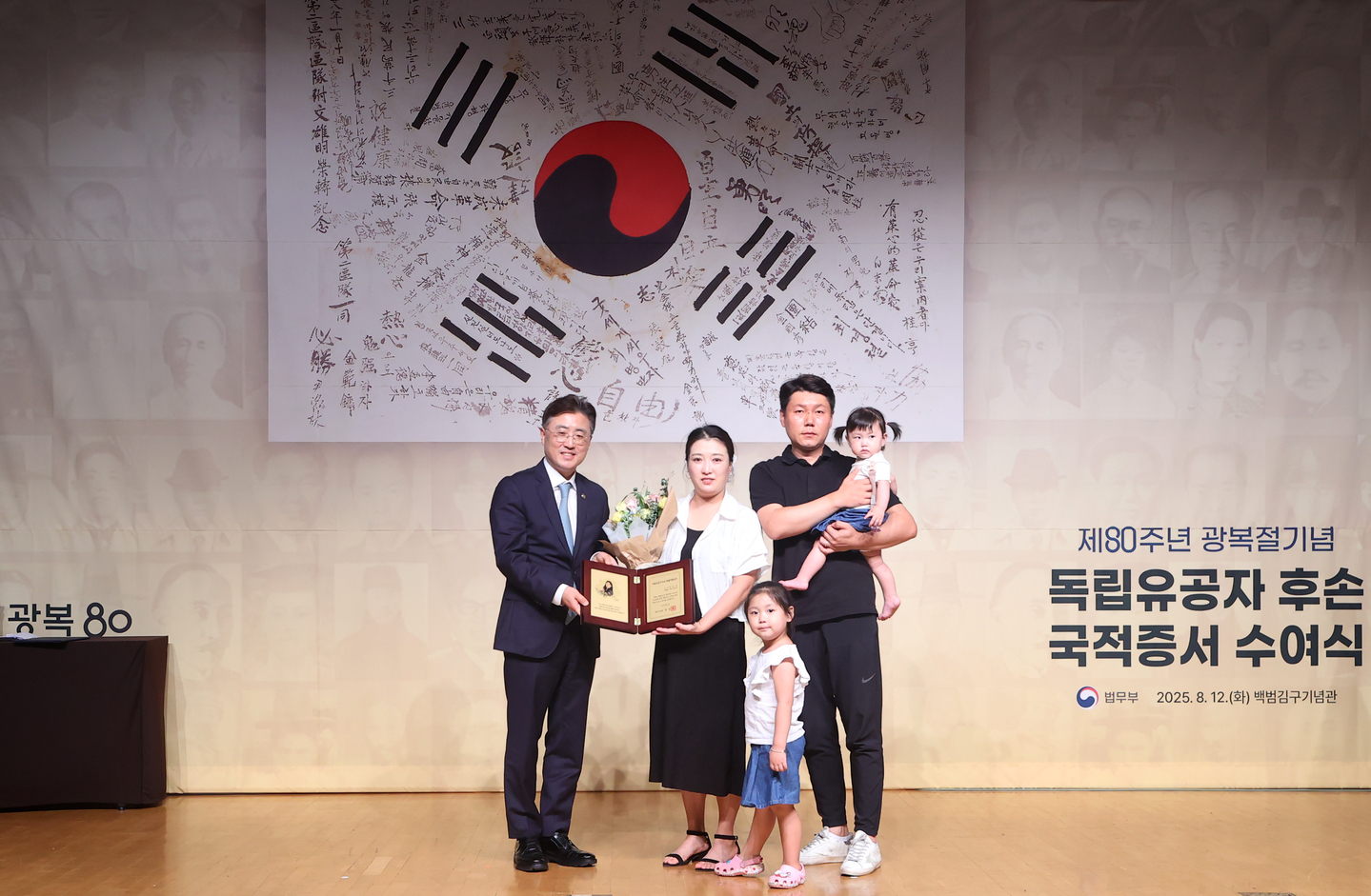 A family of naturalized Korean citizens take a commemorative photo with a Ministry of Justice official on Aug. 12, 2025. [YONHAP]