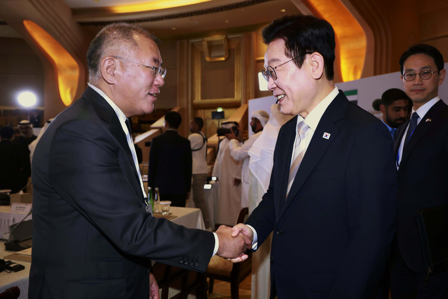 Hyundai Motor Group Executive Chair Euisun Chung, left, shakes hands with President Lee Jae Myung at a business event in Abu Dhabi on Nov. 19. [YONHAP] 