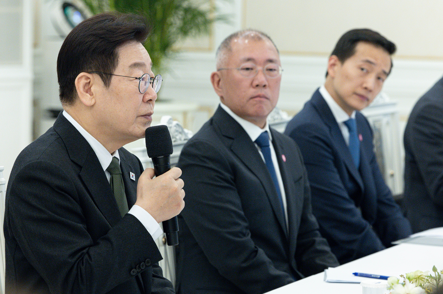President Lee Jae Myung, left, speaks as Hyundai Motor Group Executive Chair Euisun Chung, center, looks on during a meeting with the leaders of 10 major conglomerates at the Blue House in central Seoul on Feb. 4. [JOINT PRESS CORPS]