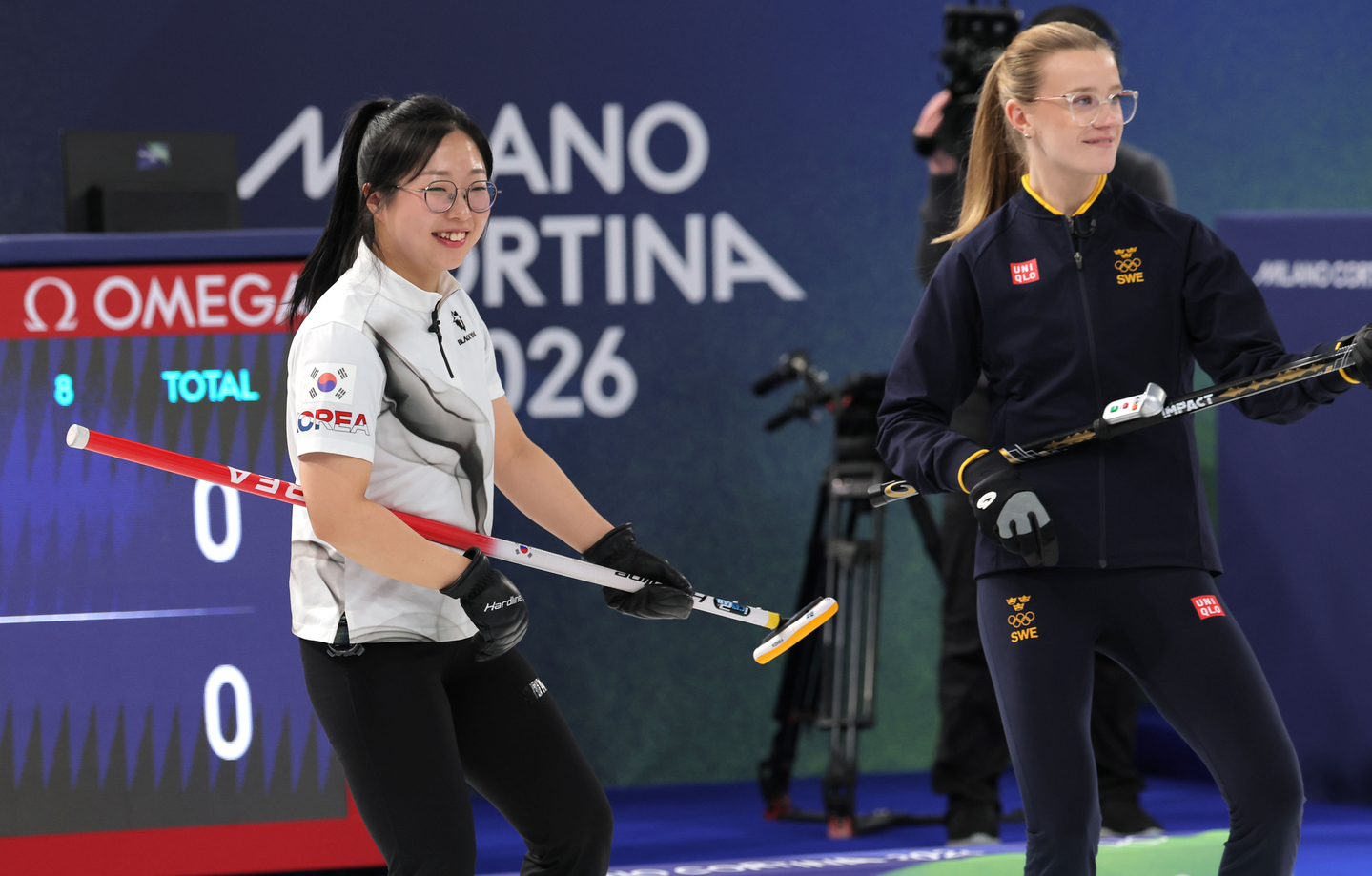 Kim Seon-yeong of Korea, left, and Isabella Wrana of Sweden play air guitar with their brooms during a stoppage of their mixed doubles curling match at the 2026 Winter Olympics at Cortina Curling Olympic Stadium in Cortina d'Ampezzo, Italy, on Feb. 4. [YONHAP] 