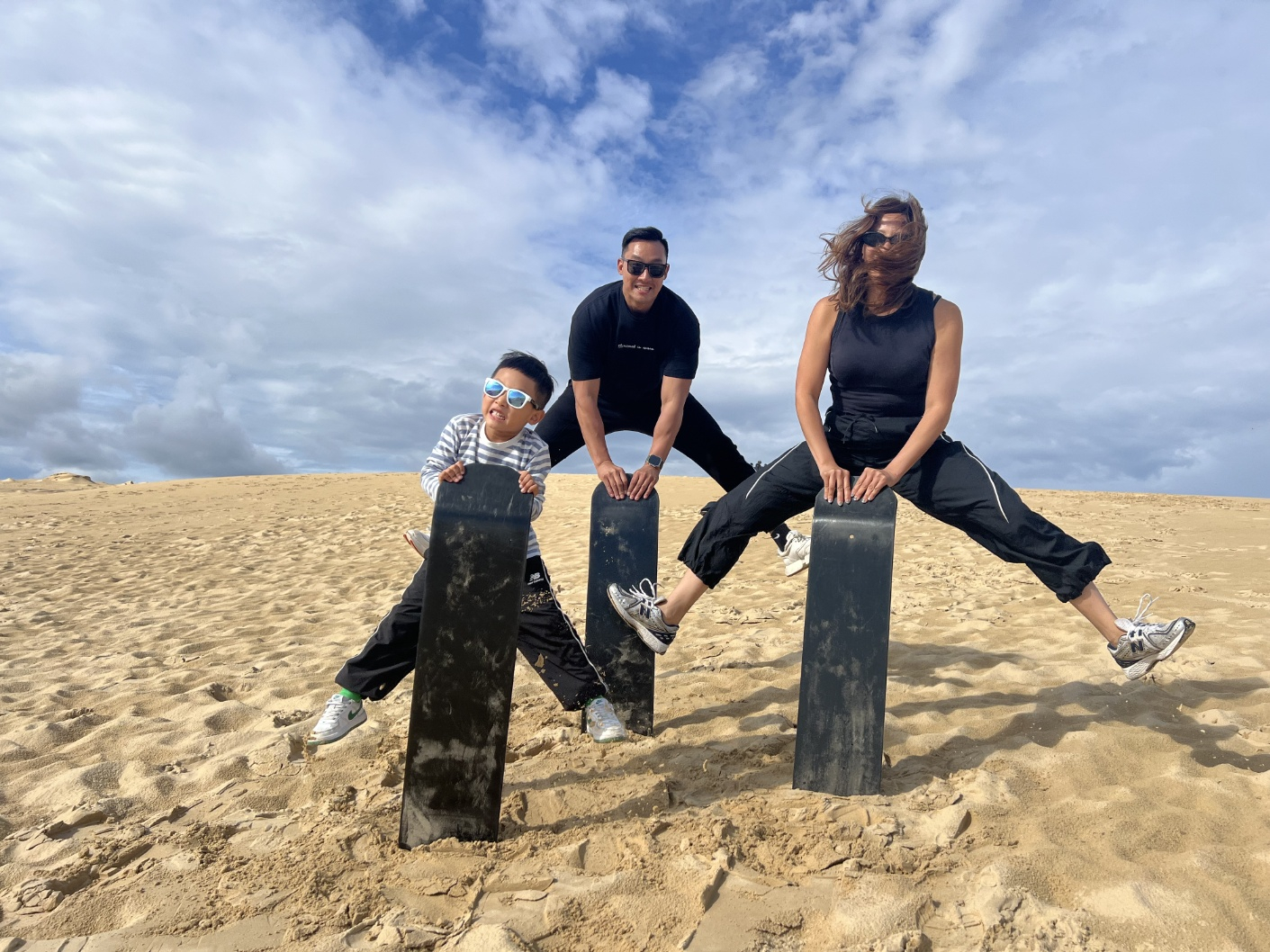 Mila Jin, far right, playfully poses for a photo with her son and husband during their sandboarding tour in Port Stephens in New South Wales, Australia, on Aug. 11, 2024. She made a month-long trip with her son to Sydney in the year. [MILA JIN]