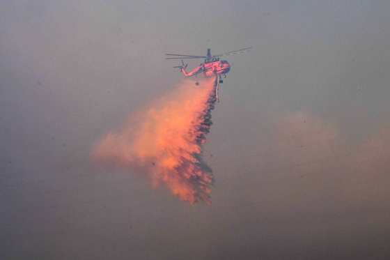 A helicopter works to contain a wildfire in Ipcheon-ri, Munmu-daewang-myeon, Gyeongju, on Feb. 8. [NEWS1]