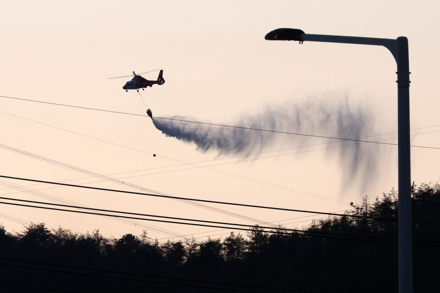 A firefighting helicopter drops water over a wildfire in Gyeongju, North Gyeongsang on Feb. 8. [YONHAP]