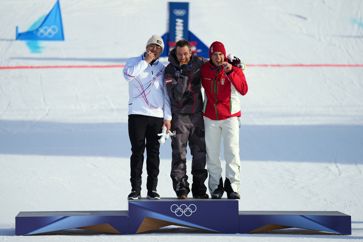 From left, silver medalist Kim Sang-kyum, gold medalist Austria's Benjamin Karl and bronze medalist Bulgaria's Tervel Zamfirov bite their medals after the men's snowboarding parallel giant slalom finals at the 2026 Winter Olympics, in Livigno, Italy, Feb. 8. [AP/YONHAP]