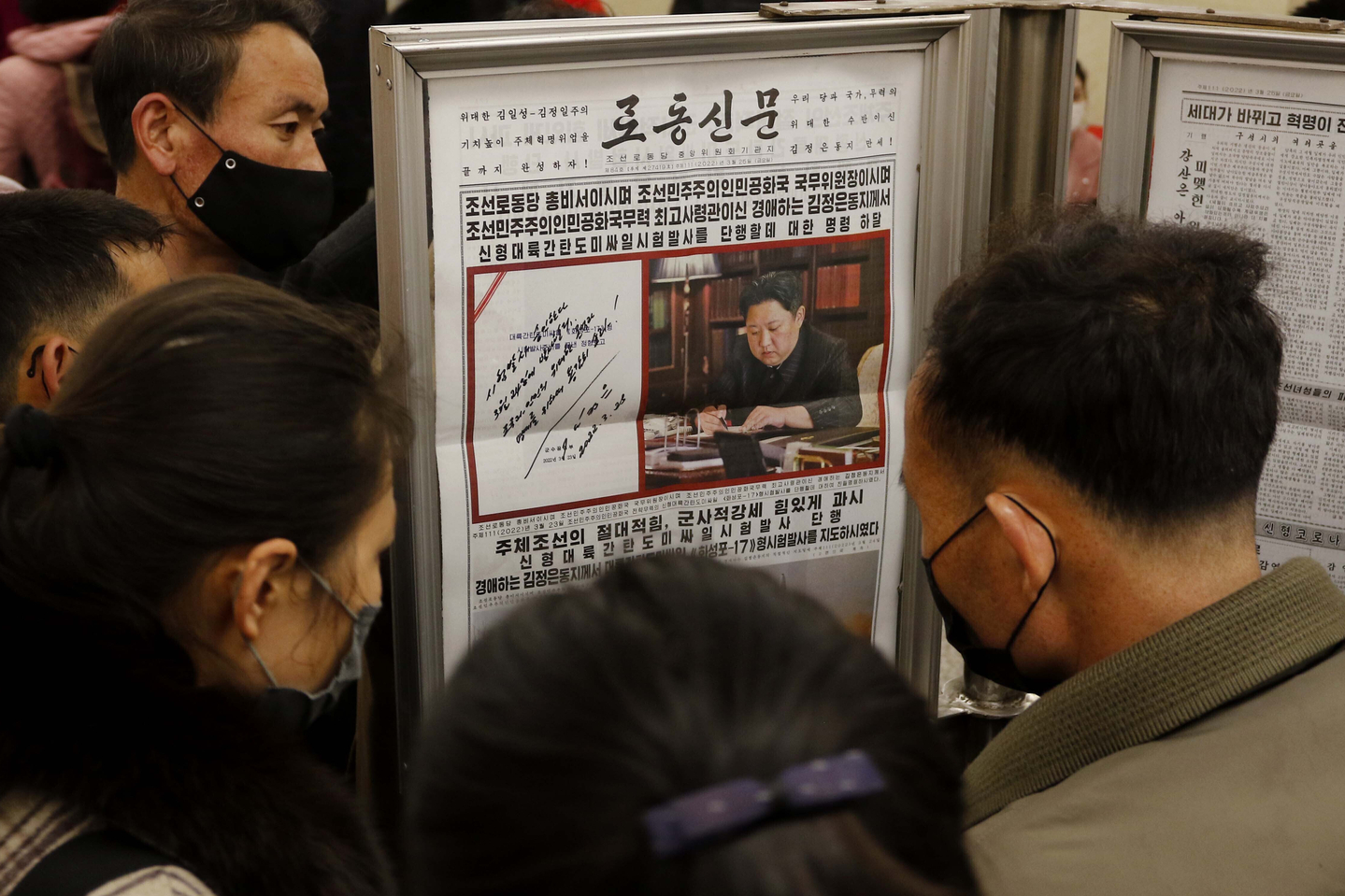 North Korean commuters look at a copy of the front page of the Rodong Sinmun at Jonsung Station in Pyongyang on March 25, 2022. [AP/YONHAP]