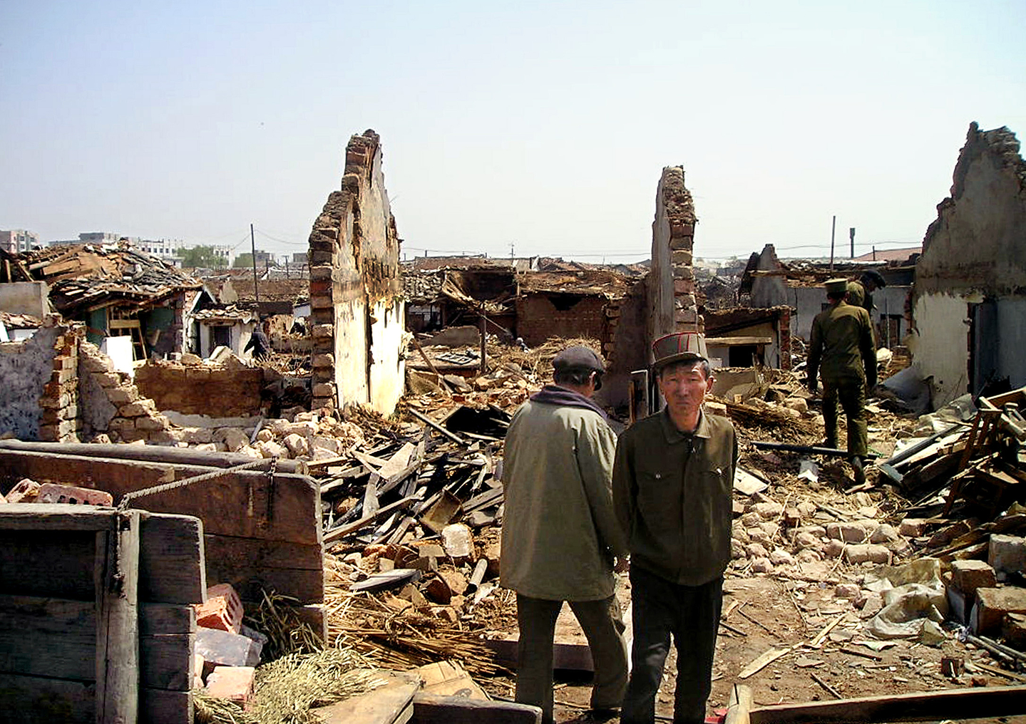 North Koreans stand in front of damaged houses near a railway station in Ryongchon, North Korea, April 24, 2004. [REUTERS/YONHAP]