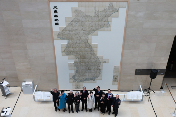 National Museum of Korea Director You Hong-june, fifth from left, poses for a photo in front of the newly installed life-size copy of the Daedongyeojido at the Path to History hallway on the first floor of the museum on Feb. 12. The Daedongyeojido, also known as the Map of the Great East, is Korea's first large-scale map created by cartographer Kim Jeong-ho in the 19th century and is listed as Korea's National Treasure No. 850. Measuring 6.7 meters (nearly 22 feet) in length and 3.8 meters in width, the map divides the Korean Peninsula into 22 sections, each compiled into a separate booklet, making it difficult to display in its entirety. [YONHAP]