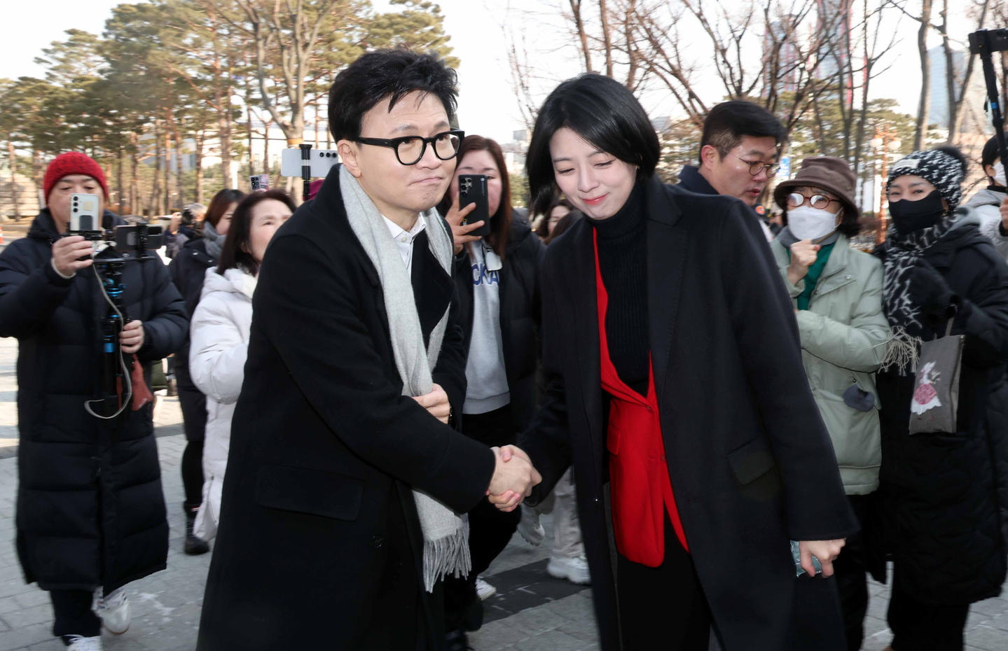 Former People Power Party leader Han Dong-hoon shakes hands with Rep. Bae Hyun-jin as he heads to the National Assembly’s press briefing room in western Seoul to speak about the party ethics committee’s decision to expel him on Jan. 14. [JOINT PRESS CORPS]