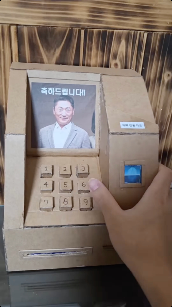 A handmade cardboard ATM designed to spit cash [SCREEN CAPTURE]