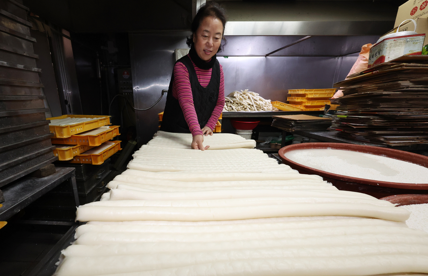 A woman prepares tteok (rice cake) which is used for tteokguk (rice cake soup), a Seollal dish, at a local market in western Seoul on Feb. 11. [NEWS1]
