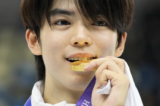 Cha Jun-hwan bites his gold medal during the victory ceremony for the men's single free skating at the 9th Asian Winter Games in Harbin, China, on Feb. 13, 2025. [AP/YONHAP]