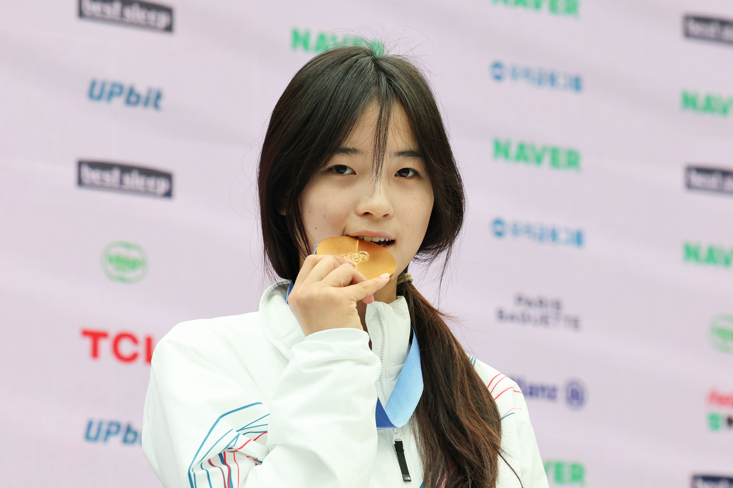 Choi Ga-on, gold medalist in the women’s snowboard halfpipe, bites her gold medal during a press conference at the Korea House set up at Villa Necchi Campiglio in Milan on Feb. 14. [KIM JONG-HO]
