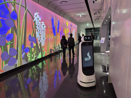 Visitors pass a media wall as a robot moves nearby at the entrance to the Seoul Gallery in central Seoul on Feb. 11. [CHO JUNG-WOO]