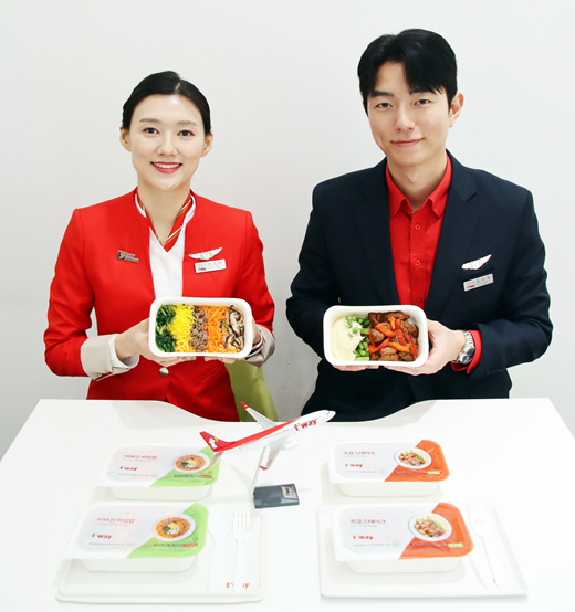 T’way Air cabin crew members introduce new in-flight meals ? ready-mixed bibimbap and pork steak ? which have been available on the airline’s long-haul routes since this month. [T'WAY AIR]