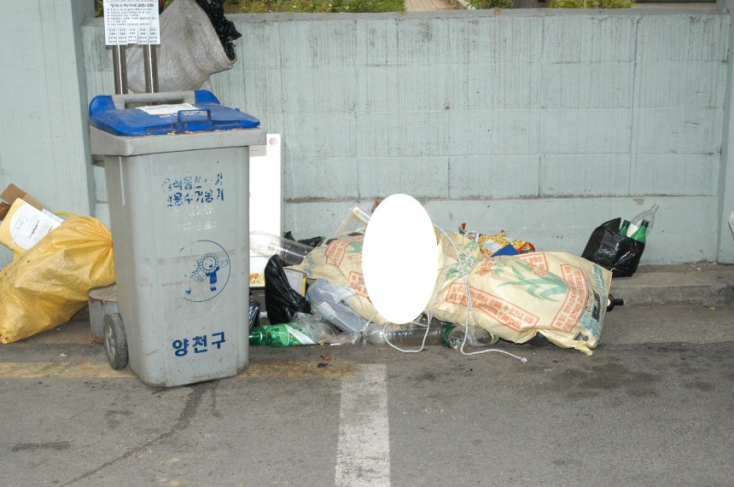 A body inside two rice burlap sacks is seen next to a garbage cart in an outdoor parking space in Sinjeong-dong in western Seoul in June 2005. [SEOUL METROPOLITAN POLICE AGENCY]