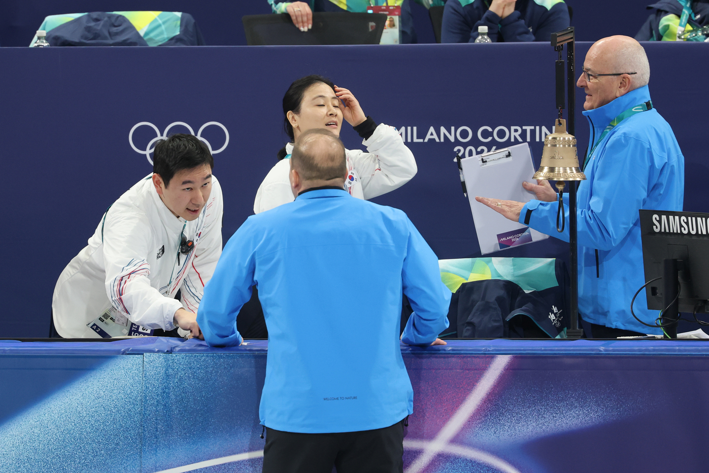 Korean national team coach Kim Min-jung, center in the back, speaks with officials after skater Kim Gil-li collided with a rival skater and fell during the mixed relay semifinal in short track speed skating at the Milan-Cortina Winter Olympics at the Milano Ice Skating Arena on Feb. 10. [YONHAP]