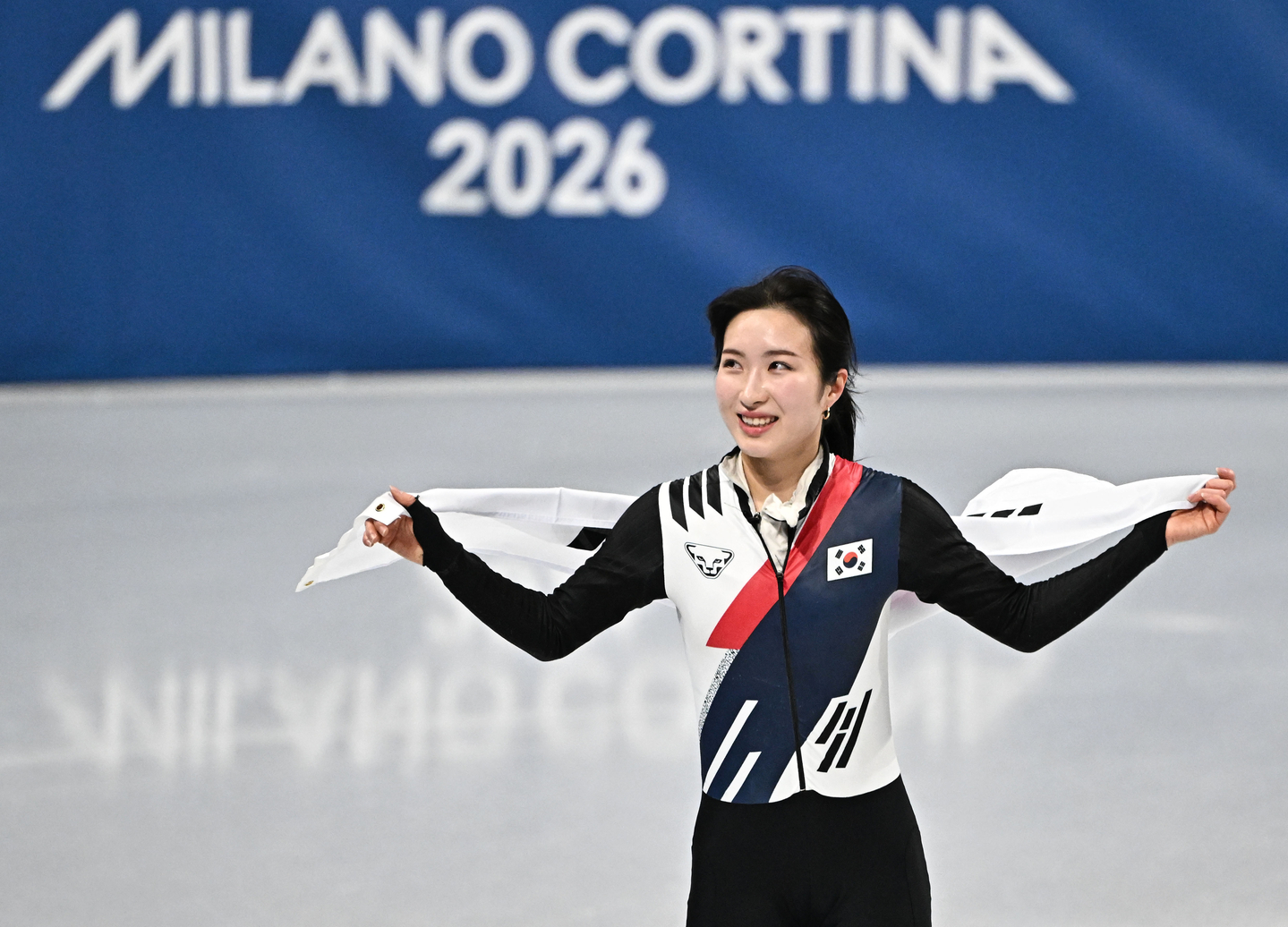  Kim Gil-li drapes herself in the national flag and greets the crowd after securing the bronze medal in the women’s 1,000 meters final at the 2026 Milan-Cortina Winter Olympics, held at the Milan Ice Skating Arena in Italy on Feb. 16. [JOONGANG ILBO] 