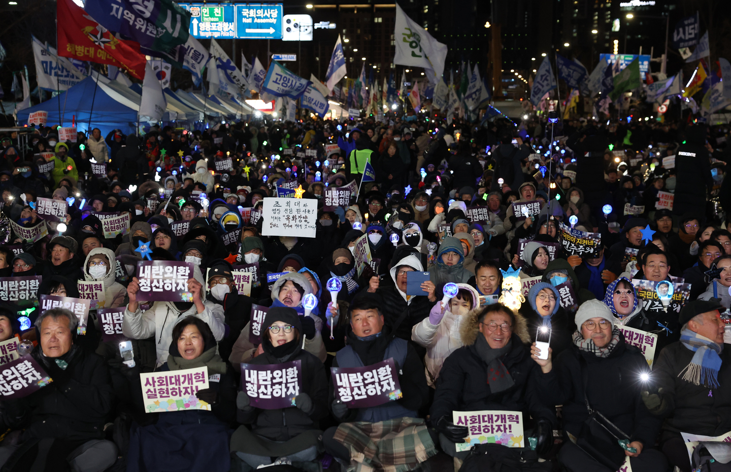 People brave the cold to hold a rally in front of the National Assembly in Yeouido, western Seoul, on Dec. 3, 2025 to mark the first anniversary of martial law imposition. The protesters held placards call for social reform and reckoning over the martial law fiasco, while others lit up the night with K-pop light sticks. [JOINT PRESS CORPS]