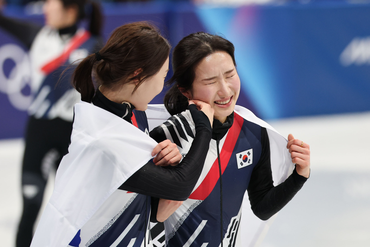 Korean short track skater Choi Min-jeong, left, brushes off tears from teammate Kim Gil-li's face after the team won the 3,000-meter relay final at the 2026 Milan-Cortina Winter Olympics at the Milan Ice Skating Arena in Milan, Italy on Feb. 18. [KIM JONG-HO] 