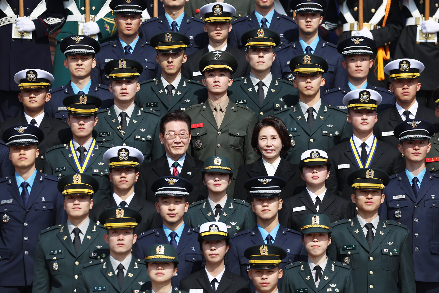 President Lee Jae Myung, center left, and first lady Kim Hea Kyung, center right, pose for a commemorative photo with newly commissioned officers during a joint commissioning ceremony of the Army, Navy and Air Force academies at Gyeryongdae, Korea's main military compound, in Gyeryong, South Chungcheong, on Feb. 20. [JOINT PRESS CORPS]