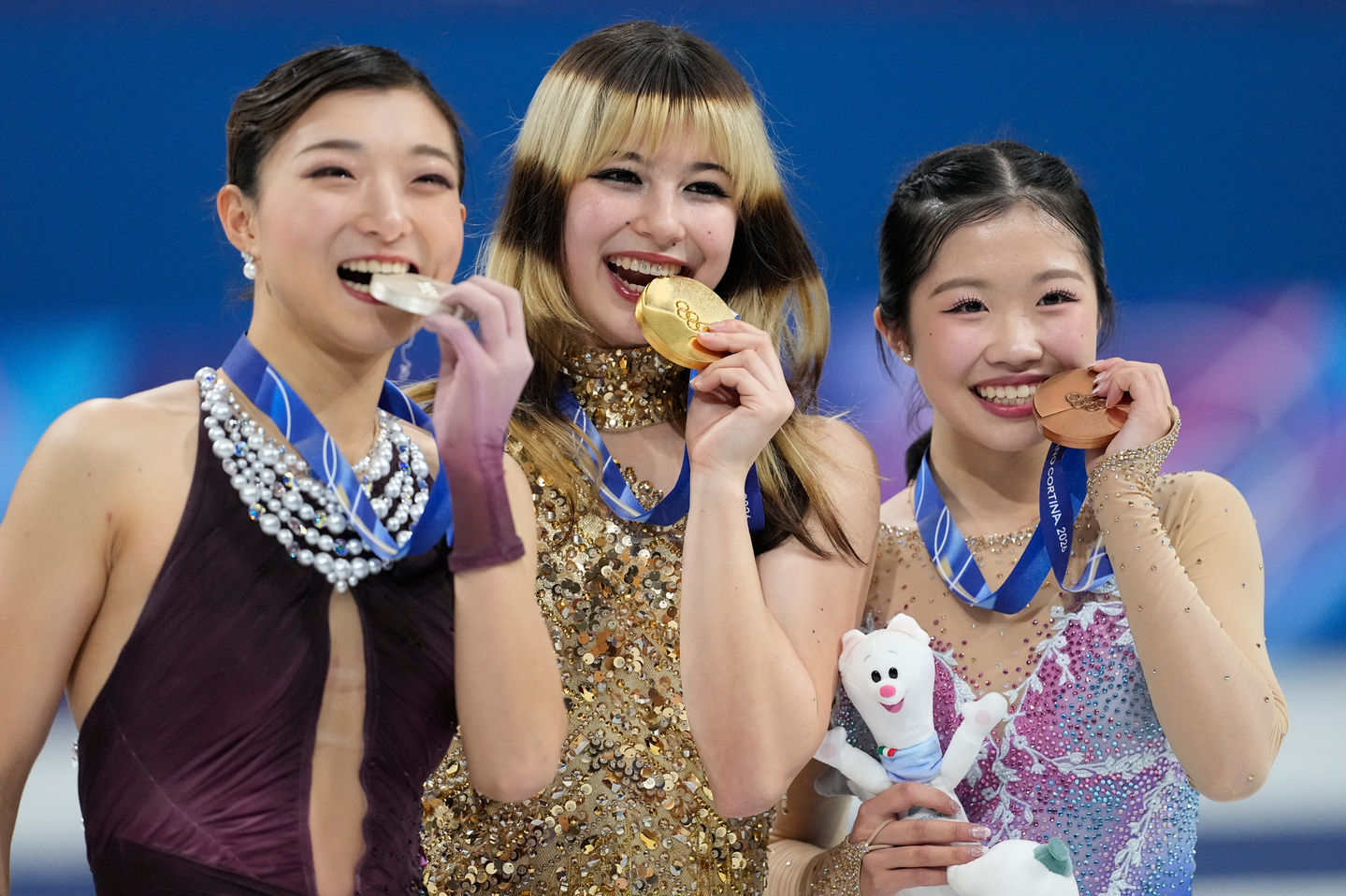 From left to right, silver medalist Kaori Sakamoto of Japan, gold medalist Alysa Liu of the United States, and bronze medalist Ami Nakai of Japan bite their medals after competing in the women's free skate program in figure skating at the 2026 Winter Olympics in Milan on Feb. 19. [AP/YONHAP]