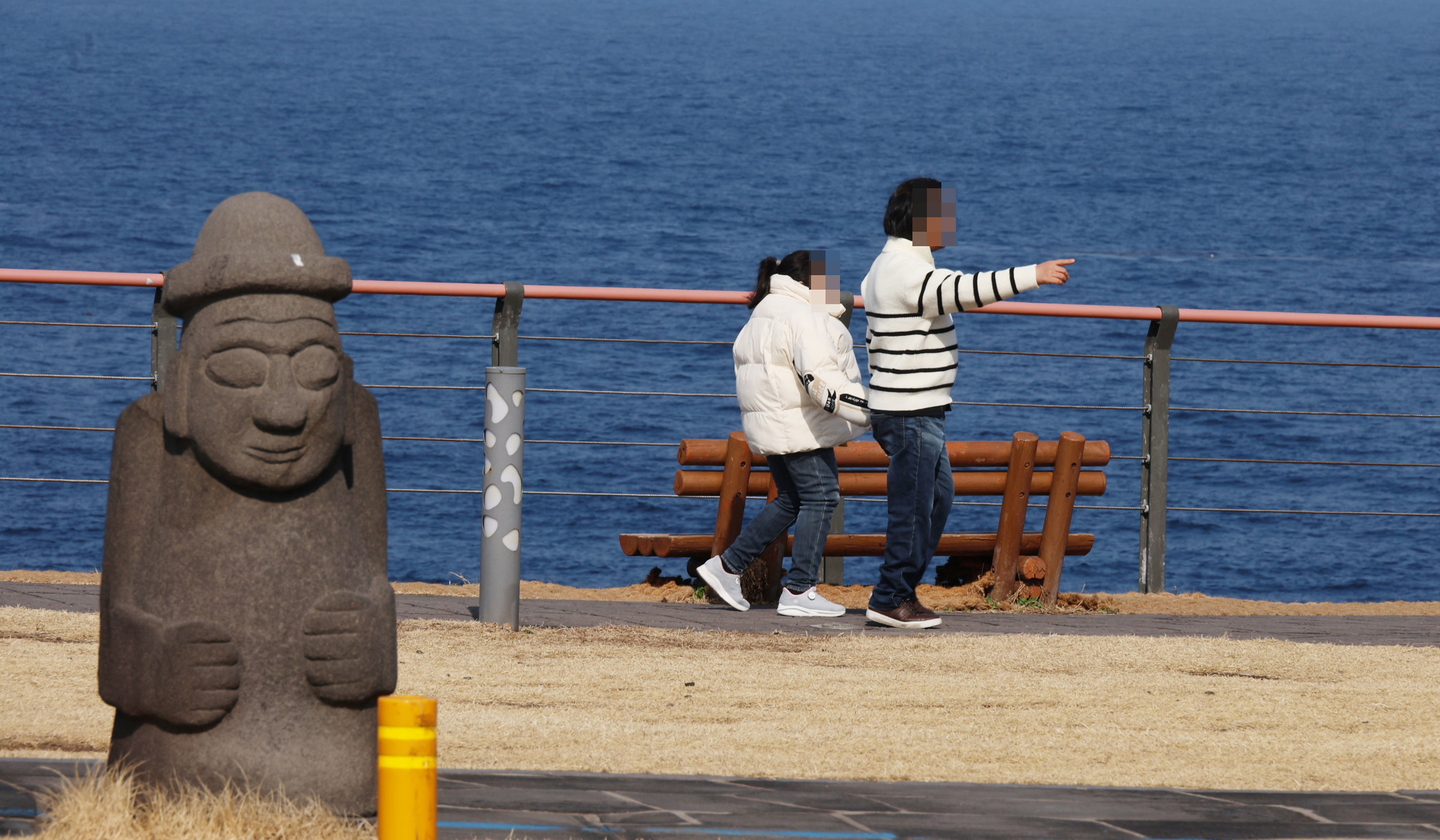 Pedestrians walk alongside the ocean in Jeju Island on Feb. 15. [YONHAP]