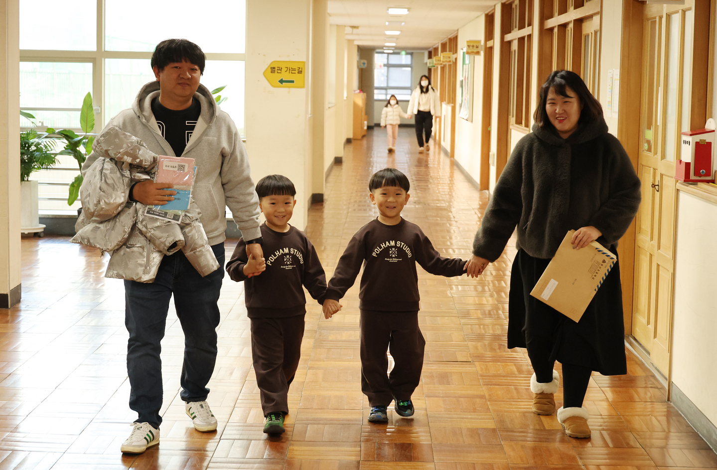 Twin prospective students and their parent look around a first-grade classroom at Changshin Elementary School in Busan on Jan. 6. [YONHAP]