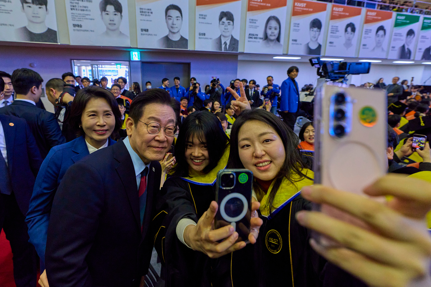 President Lee Jae Myung, left, takes selfies with graduates after a KAIST commencement ceremony at the school’s campus in Daejeon on Feb. 20. [JOINT PRESS CORPS]
