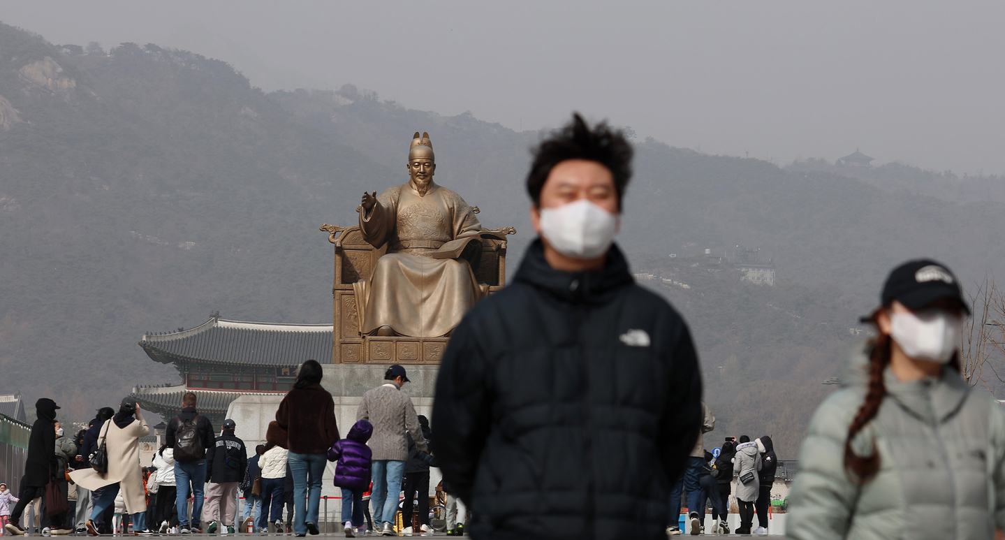 People wear masks and walk around Gwanghwamun Square in central Seoul as yellow dust sweeps the nation on Feb. 22. [YONHAP]