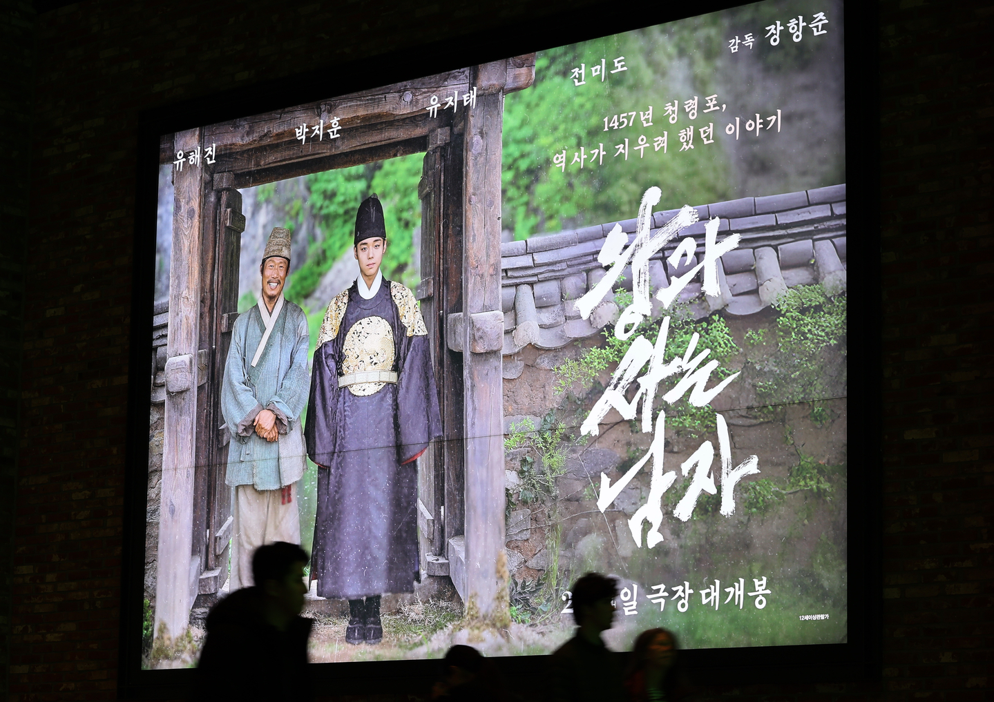 People walk in front of a promotional poster for the historical drama film ″The King's Warden″ at a movie theater in Seoul on Jan. 22. [YONHAP] 