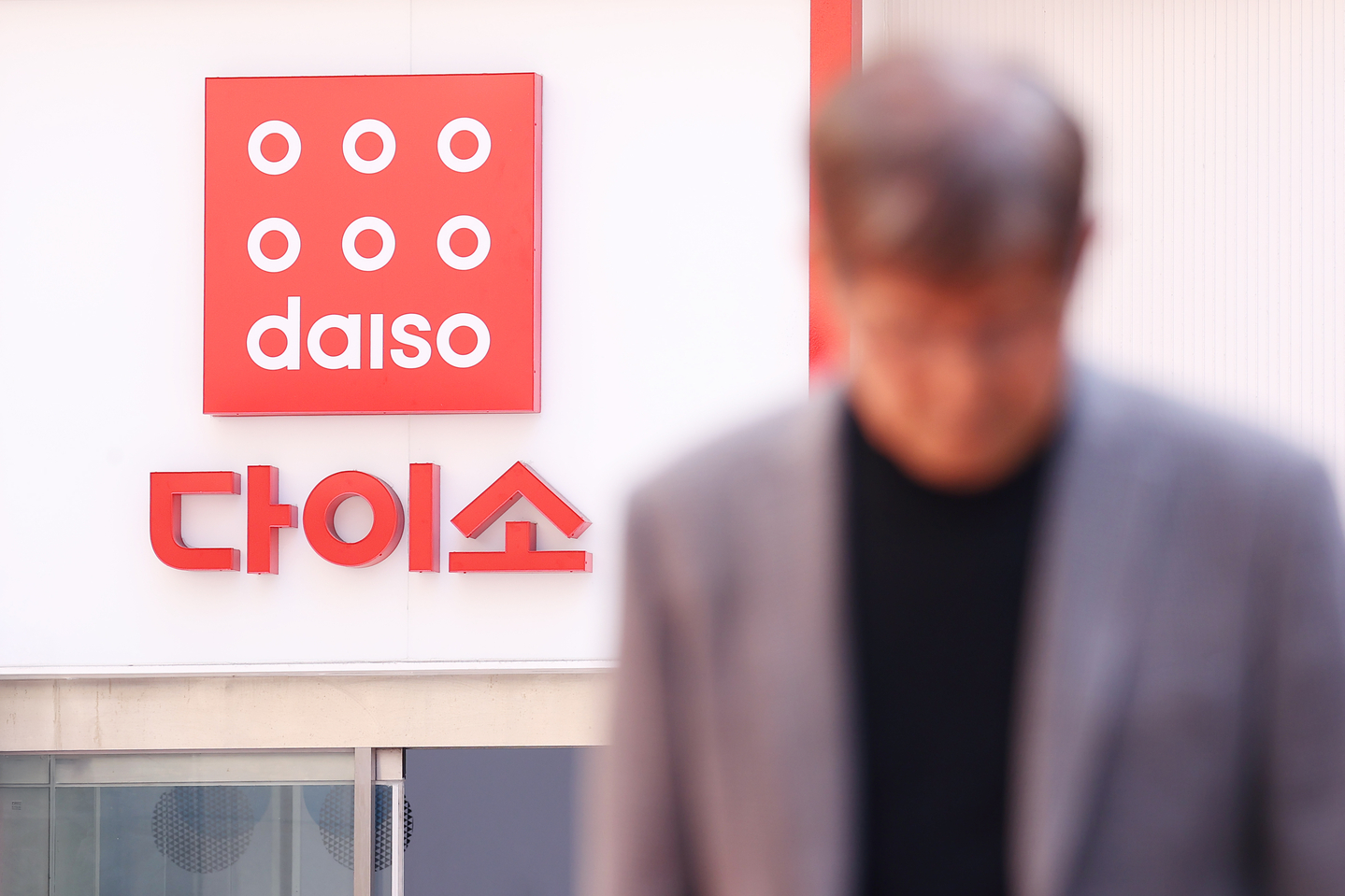 A passerby walks past a Daiso sign hanging on the store in Seoul on April 15, 2025. [YONHAP]
