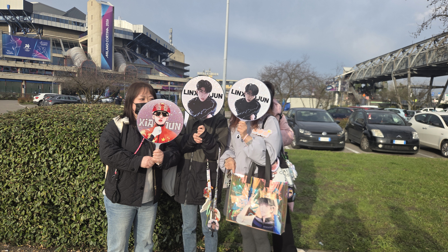 Chinese supporters of Lin Xiaojun hold up fans with the short track speed skater's face in front of the Milano Ice Skating Arena in Italy. [PARK LIN]