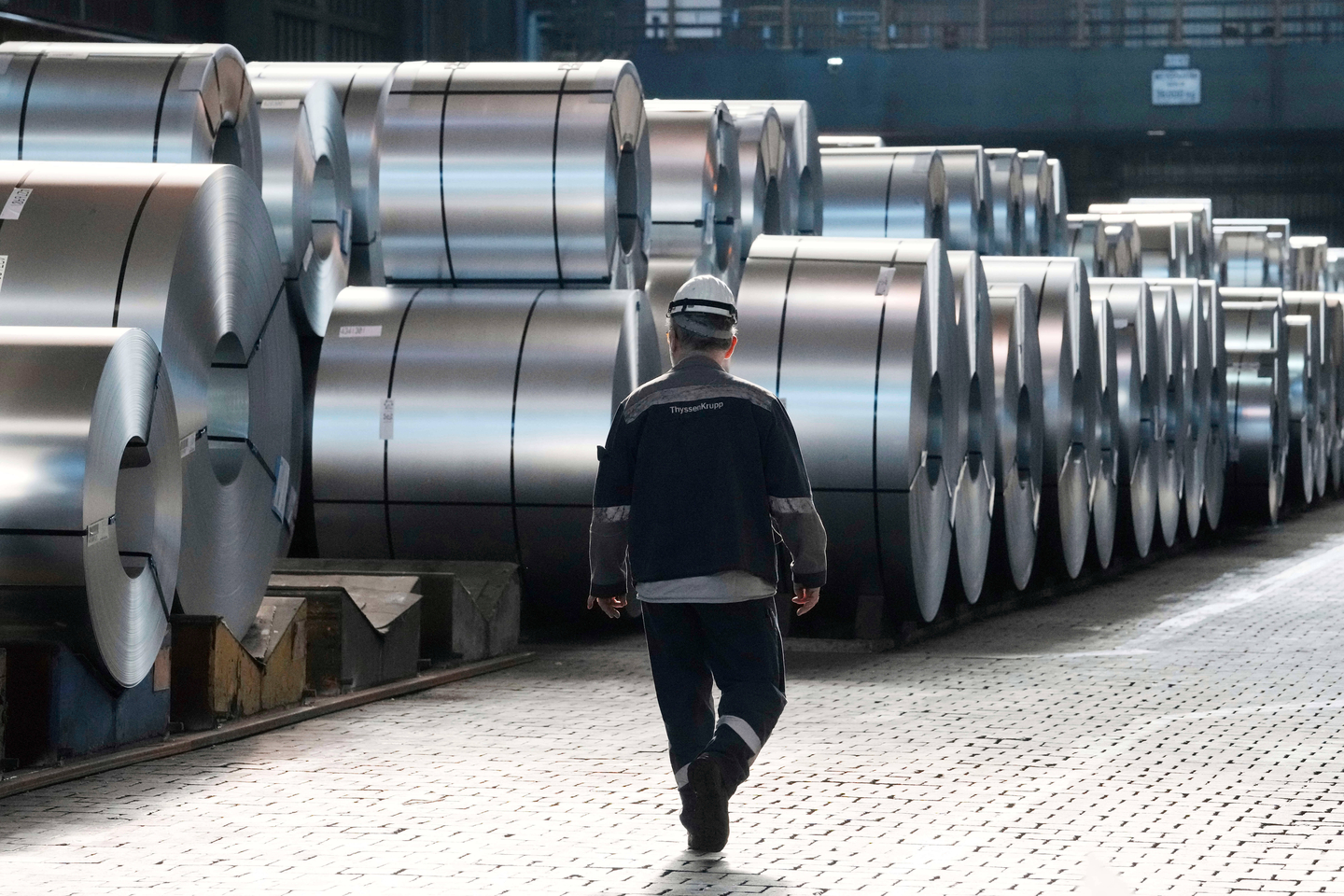 A steel worker walks beside steel coils during a visit of EU Commissioner for Prosperity and Industrial Strategy Stephane Sejourne at the Thyssenkrupp steelworks in Duisburg, Germany, after the EU Steel Action plan was presented, on March 20, 2025. [AP/YONHAP]