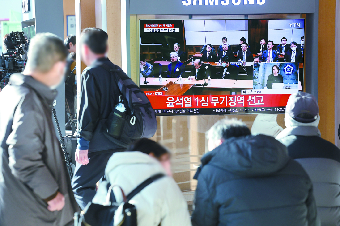 Citizens watch a live TV broadcast of the first trial verdict for former President Yoon Suk Yeol at Seoul Station on Feb. 19. Yoon was indicted on charges of leading an insurrection in connection with the Dec. 3, 2024, martial law declaration. [YONHAP]