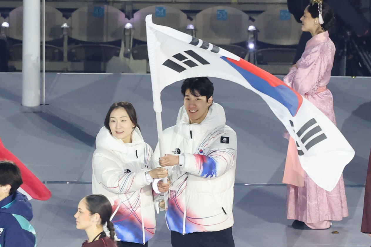 Korean short track speed skaters Choi Min-jeong, left, and Hwang Dae-heon carry the national flag during the closing ceremony of the Milan-Cortina Winter Olympics at Verona Olympic Arena in Verona, Italy, on Feb. 22. [YONHAP]