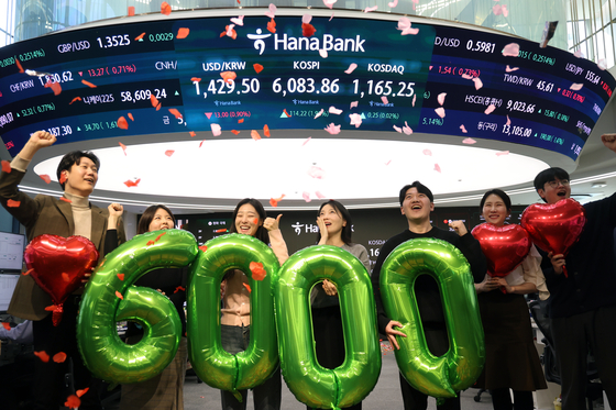 Employees celebrate at the dealing room of Hana Bank’s headquarters in Jung District, central Seoul, on Feb. 25 after the Kospi closed above the 6,000 mark for the first time. [NEWS1]
