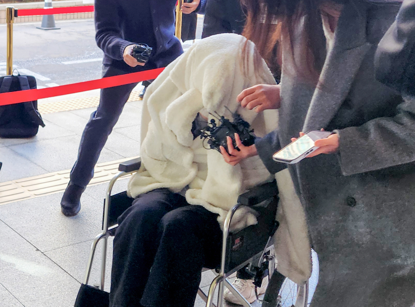 A woman suspected of being under the influence of drugs while crashing a Porsche off Banpo Bridge appears for a hearing at the Seoul Western District Court in Mapo District, western Seoul, on Feb. 27, covering her face with a blanket while in a wheelchair. [YONHAP]