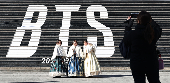 Tourists take a photo in front of a promotion for BTS's new album, "Arirang," at the Sejong Center for the Performing Arts in Jongno District, central Seoul, on Jan. 22. [YONHAP] 