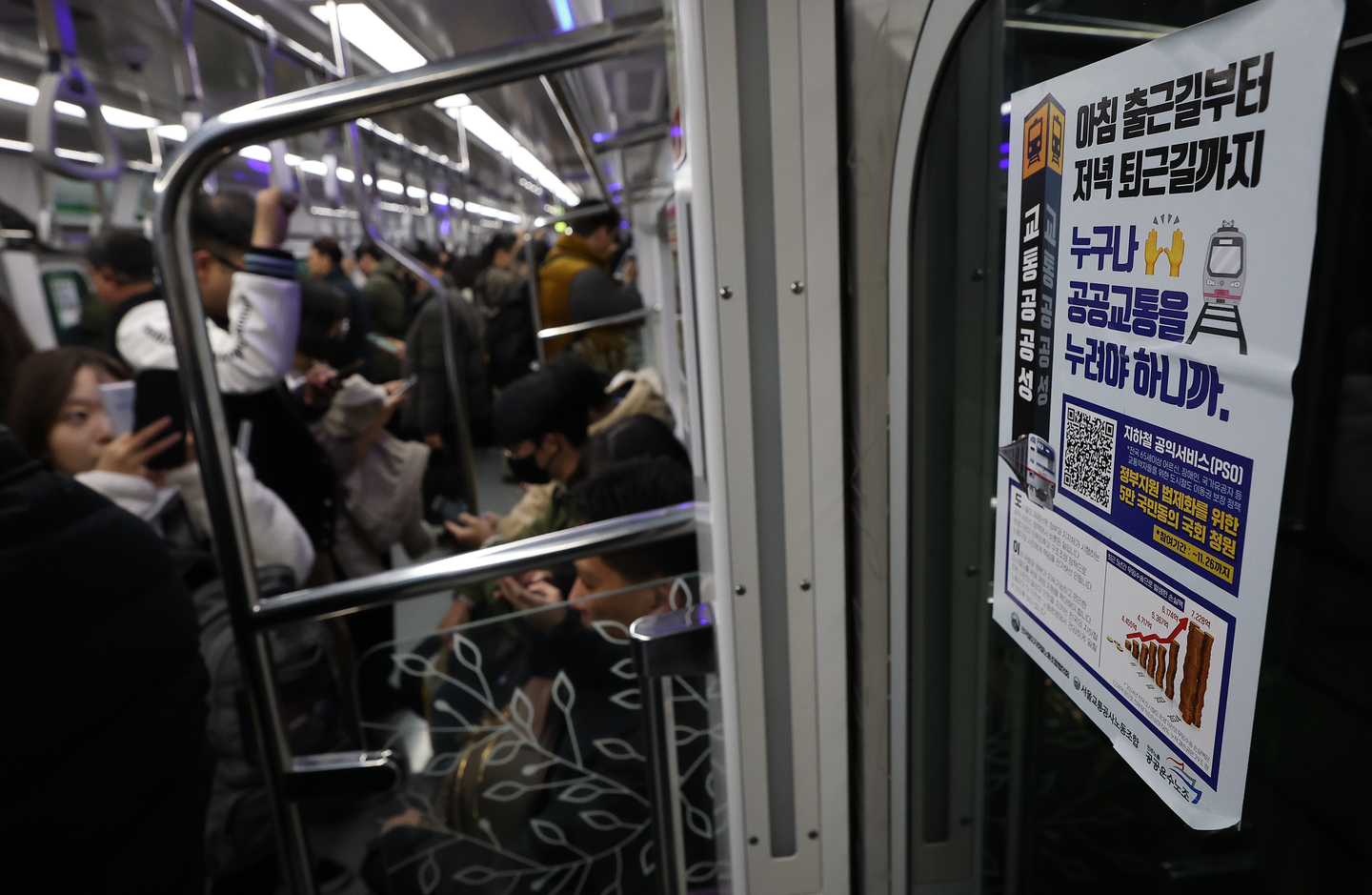 Commuters sit and stand inside a subway car in Seoul on Dec. 1, 2025. [YONHAP]