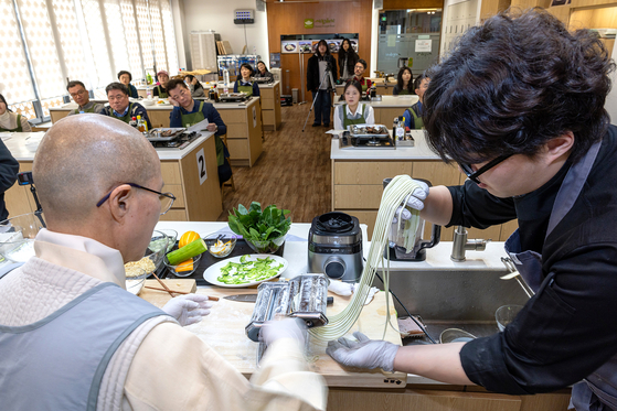 Vernerable Seonjae makes noodles with a staff during a media event held at the Temple Cuisine Culture Experience Center in Jongno District, central Seoul, on Feb. 26 [CULTURAL CORPS OF KOREAN BUDDHISM]