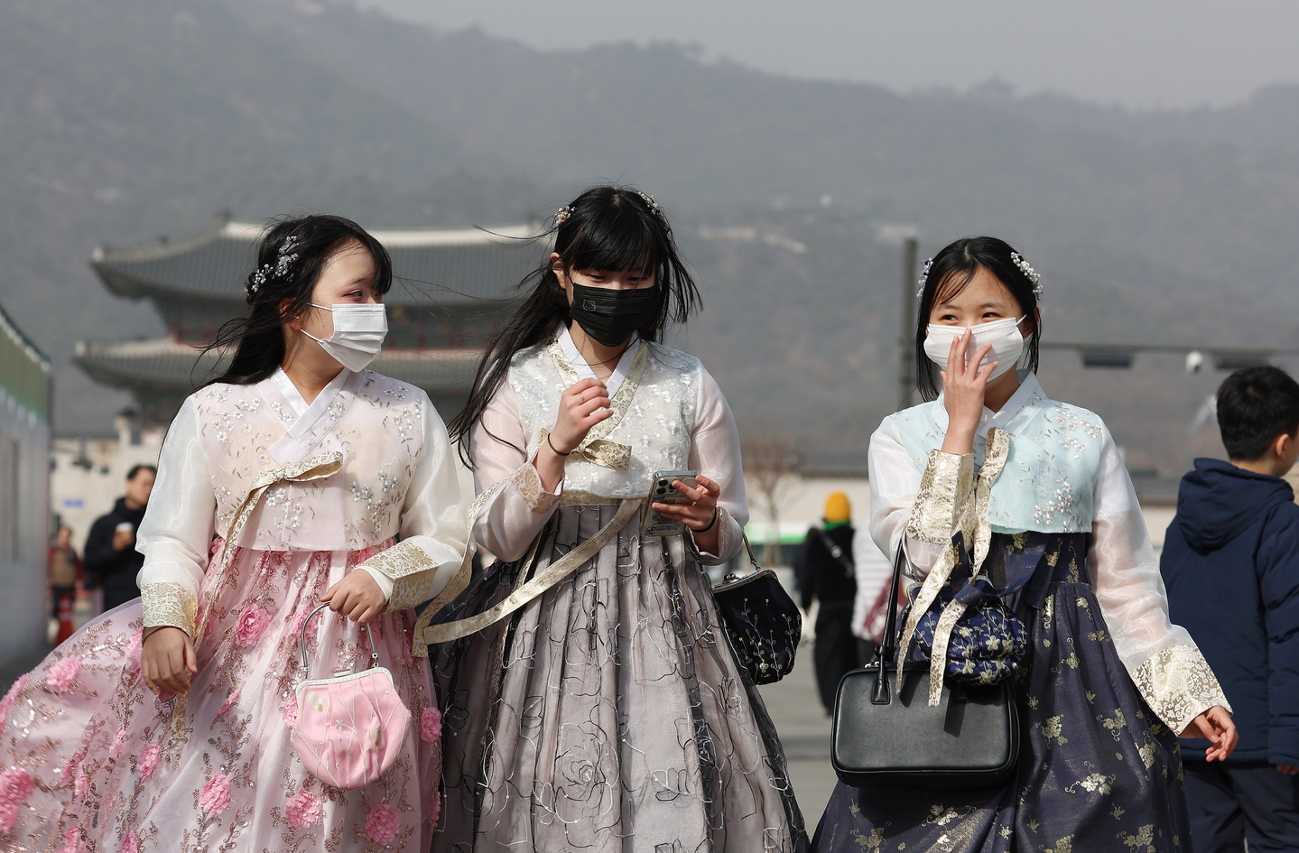 Pedestrians wearing masks walk through Gwanghwamun Square in central Seoul on Feb. 22, as a fine dust advisory is issued for Seoul, Incheon and Gyeonggi due to yellow dust. [YONHAP]