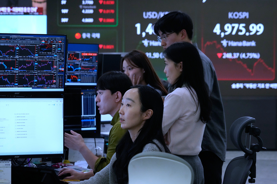 Currency traders watch monitors near a screen showing the Korea Composite Stock Price Index (Kospi), top right, at the foreign exchange dealing room of the Hana Bank headquarters in Seoul, Korea on Feb. 2. [AP/YONHAP]