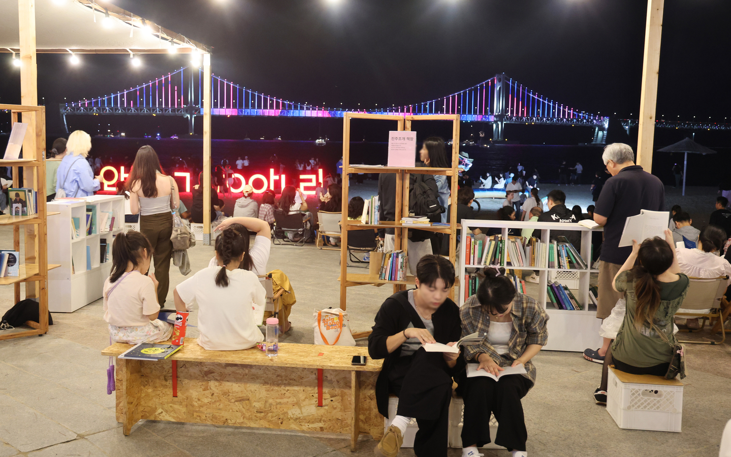 People read books themed around the sea at the “Beach Book Lounge” during the Gwangalli Beach Book Fair, held at Manam Plaza on Gwangalli Beach in Busan on the afternoon of Sept. 20, 2025. [YONHAP]