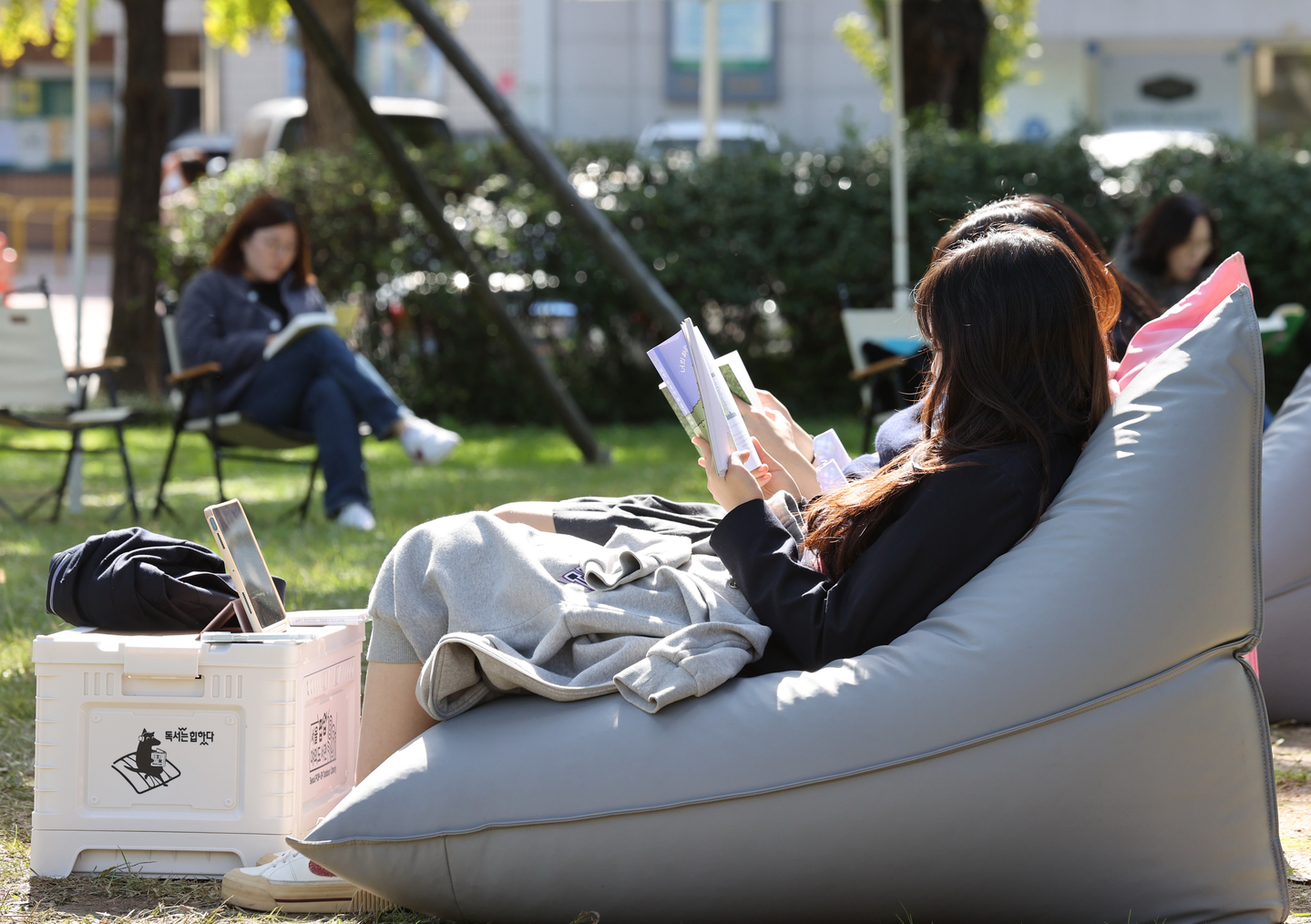 People read at Asia Park in Songpa District, southern Seoul, as part of the district's outdoor library campaign on Oct. 23, 2025. [YONHAP]