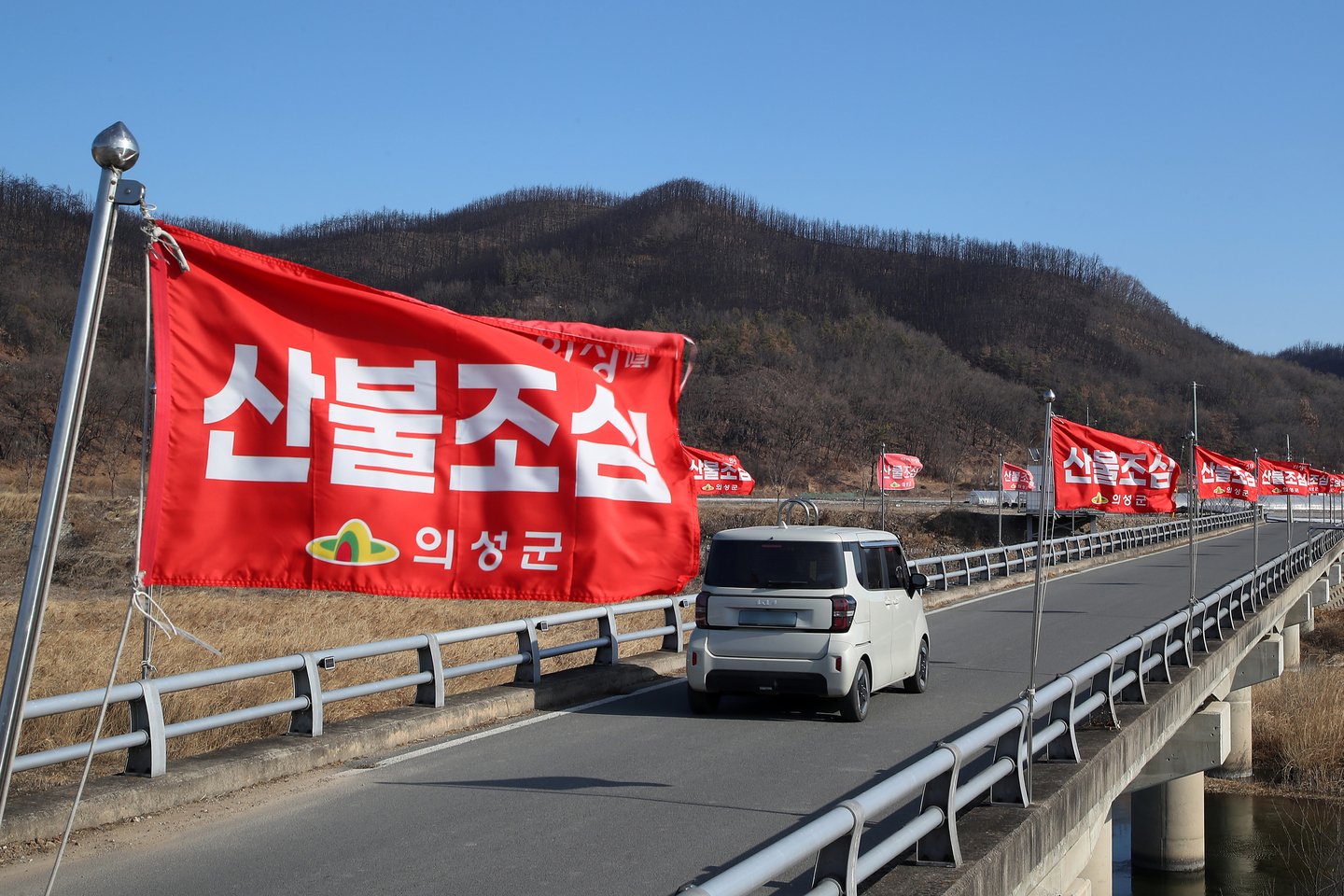 A wildfire warning flag flutters in the wind in front of a hillside in Uiseong County, North Gyeongsang, on Jan. 29. [NEWS1]